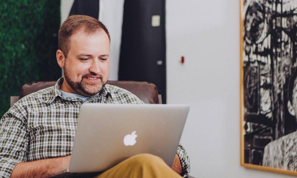 man smiling and using MacBook